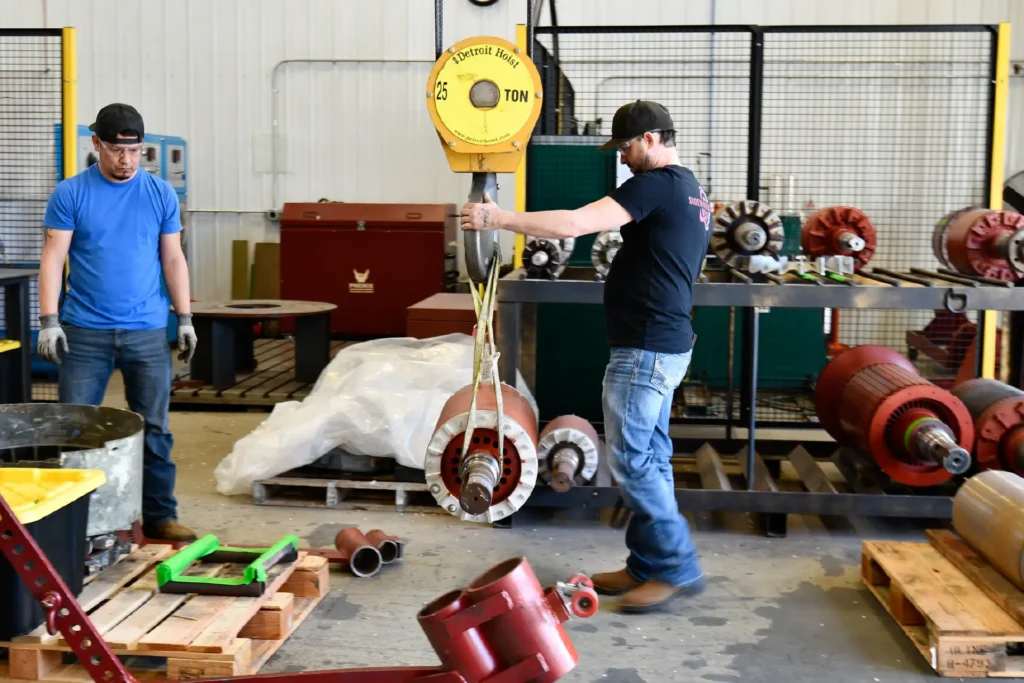 Sidewinders moving heavy rotor part with crane.